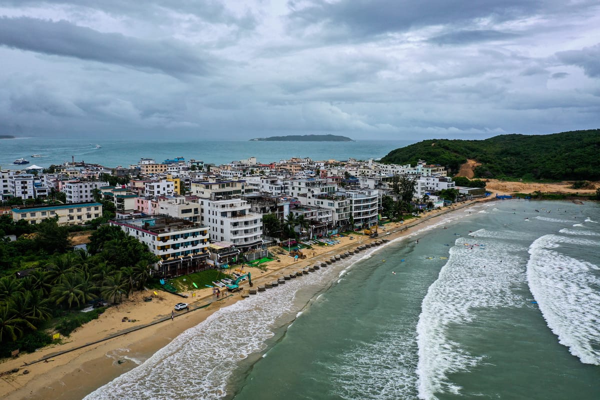 Aerial view of a Sanya beach with palm trees, resort towers and turquoise bay in Hainan, China