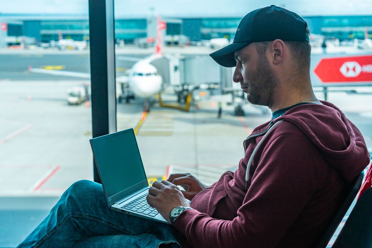 Traveller setting up a laptop at the airport gate before a flight