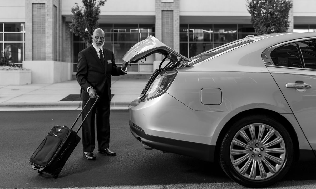 A pre-booked driver loading luggage for an airport transfer