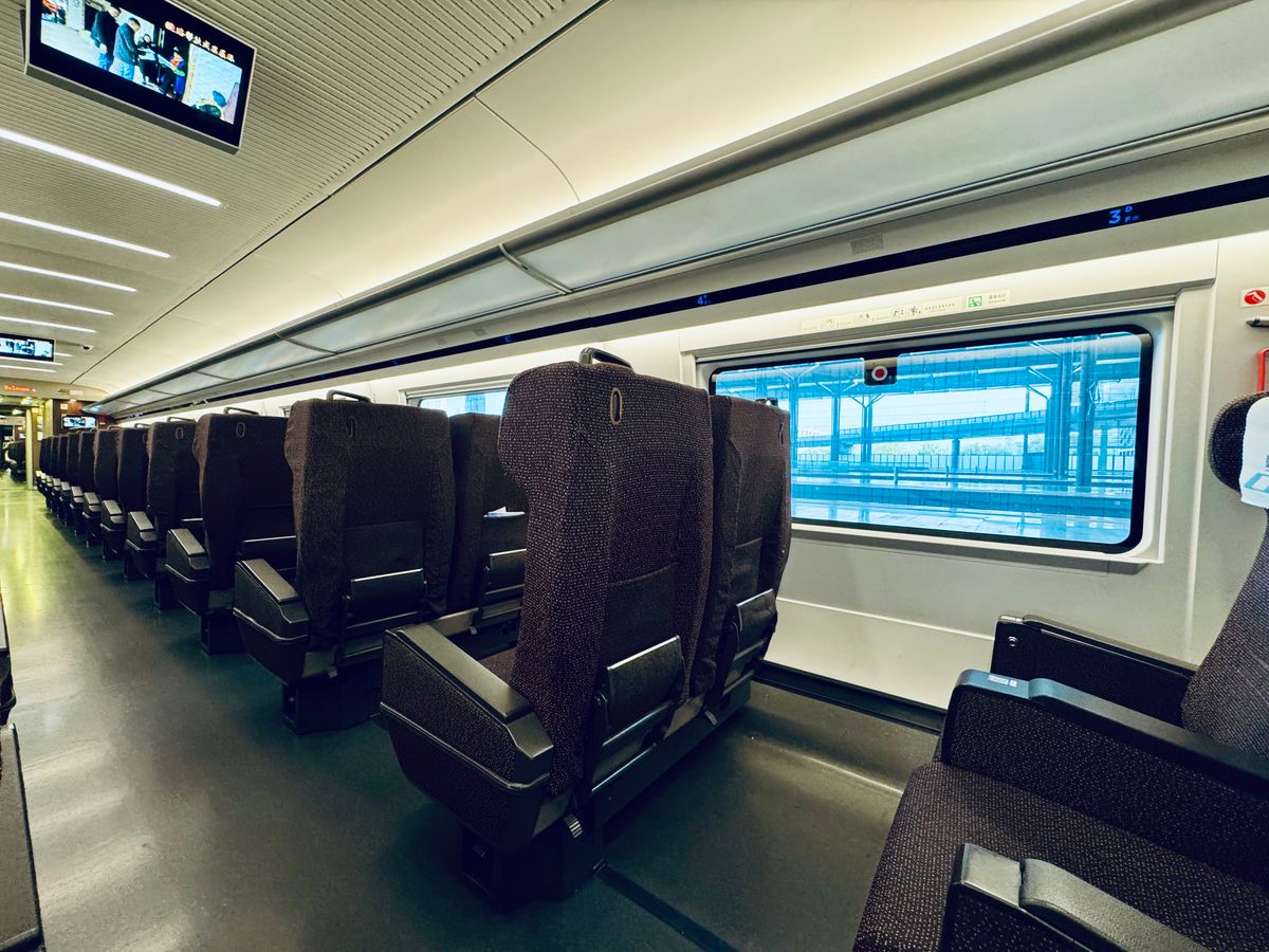 Interior of a modern Chinese high-speed train with rows of reclining seats beside a large window