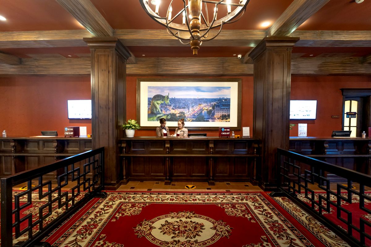 A hotel reception desk with two staff members assisting at check-in