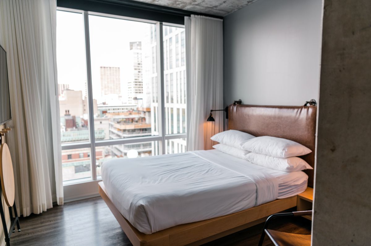 A modern hotel room with a large window overlooking a city skyline