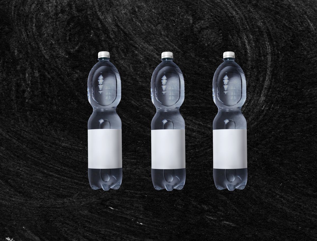 Three sealed plastic bottles of still water with blank labels arranged on a dark background