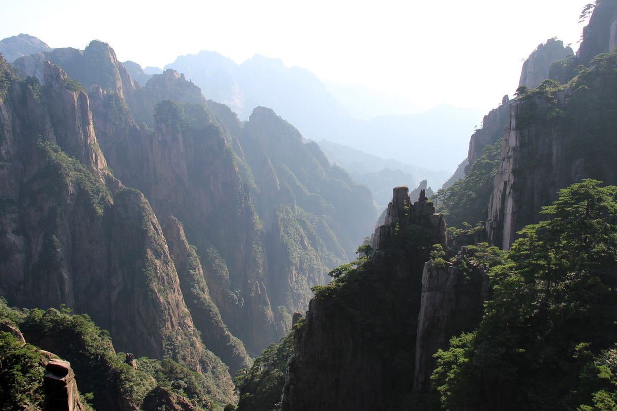 Jagged granite peaks and pine-filled valleys of Huangshan under a hazy sky