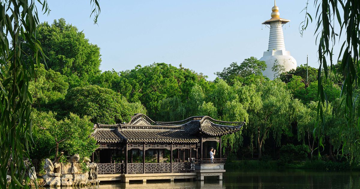 Lakeside pavilion framed by willows with the White Dagoba beyond