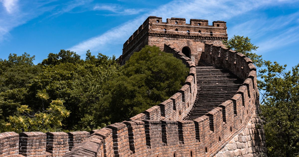 Stone watchtower and battlements of the Mutianyu Great Wall under a blue sky