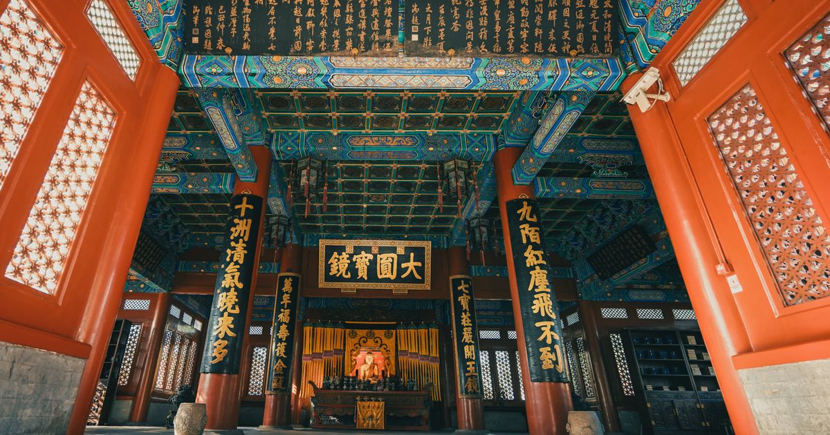 Ornate interior hall of the Lama Temple with painted beams and calligraphy