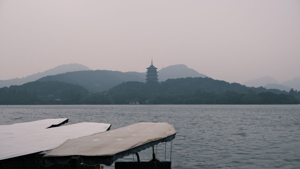 Misty view of West Lake with a traditional boat