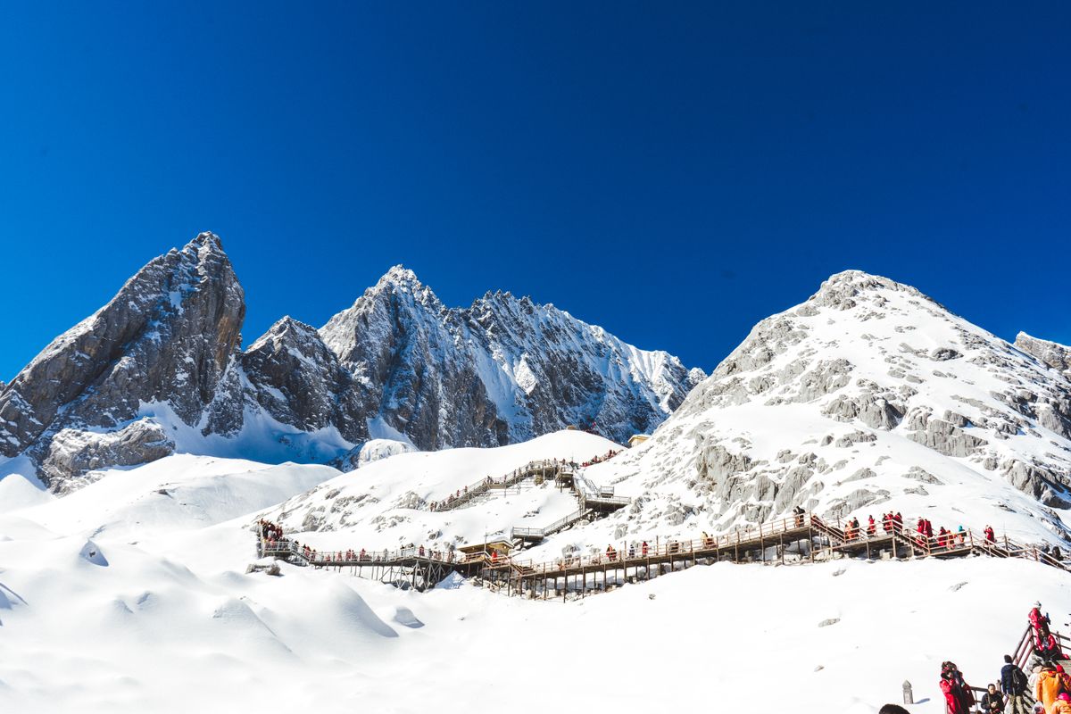 Visitors on the glacier boardwalk below the peaks of Yulong
