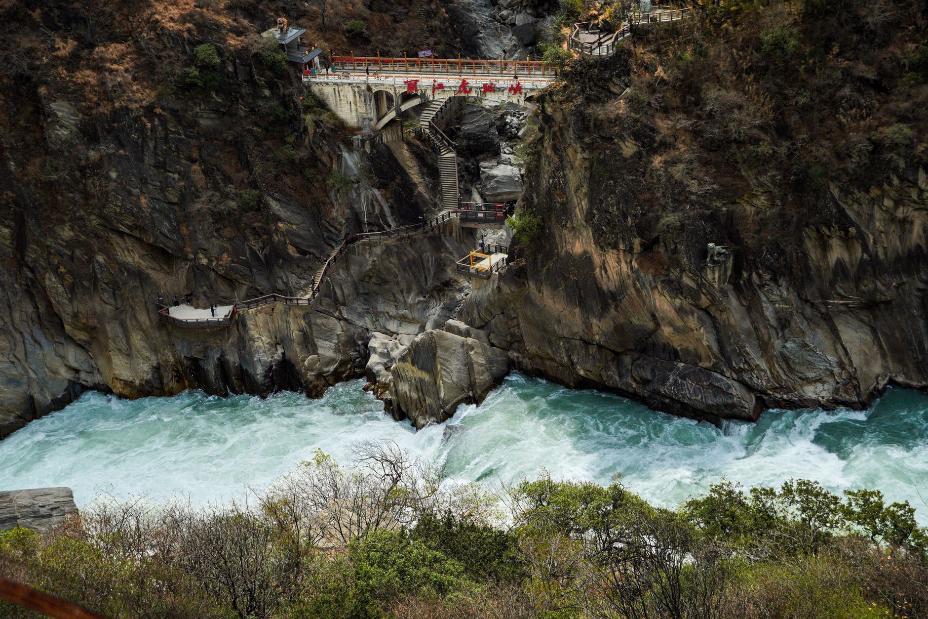 Hikers on a cliffside boardwalk above the gorge