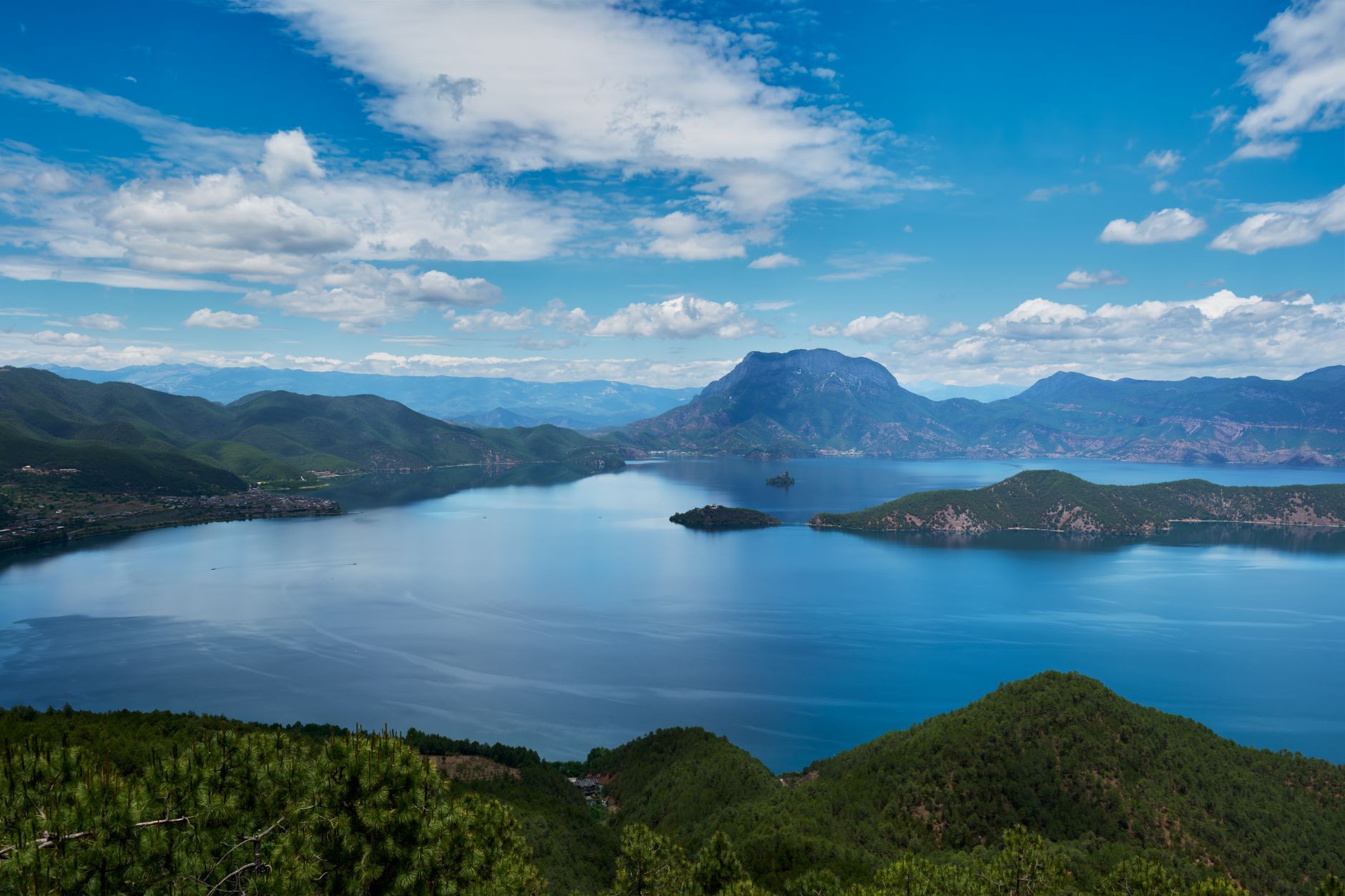 Panorama of deep-blue Lugu Lake with islands and the Gemu Goddess Mountain