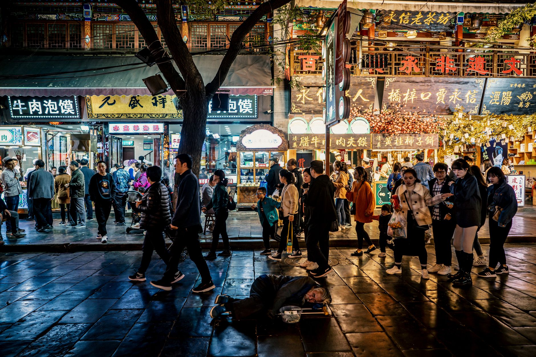 A bustling night-market lane in the Muslim Quarter, hung with food-stall signs