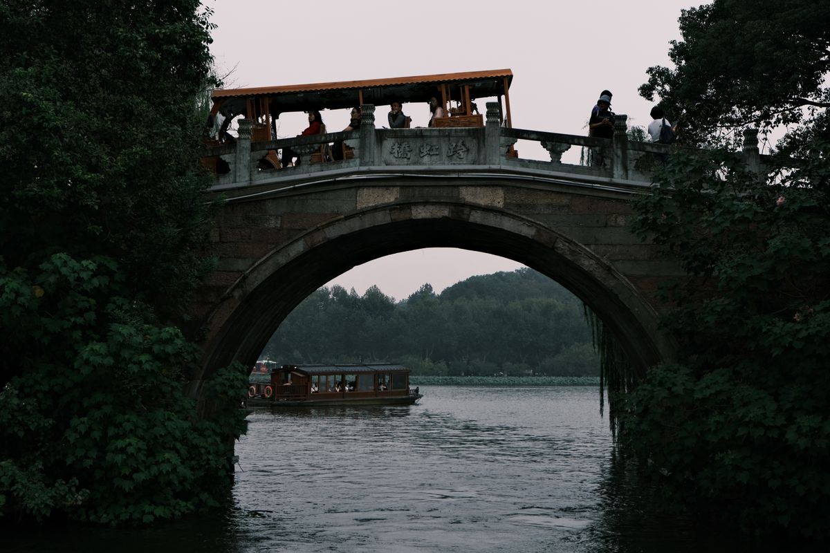 The Grand Canal in Hangzhou with traditional houses, a stone arch bridge and modern towers