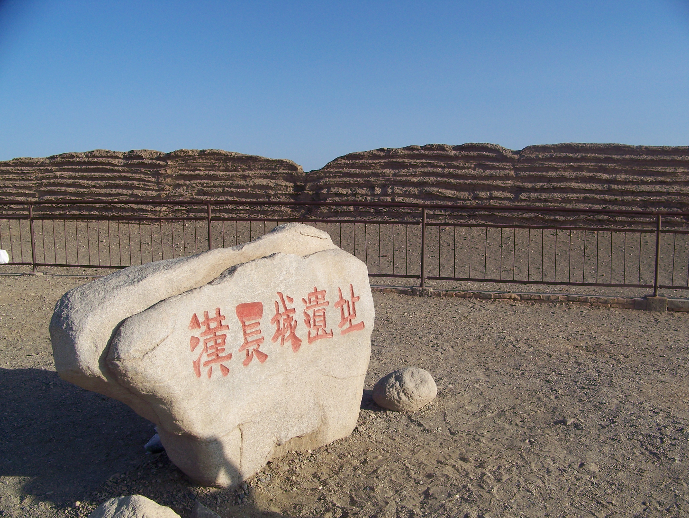 Site marker stone reading "Han Great Wall Ruins" before the layered wall