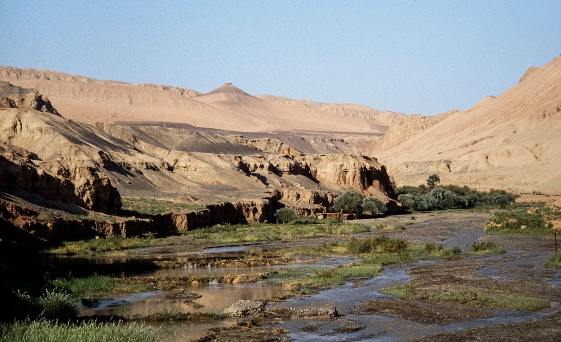 Arid cliffs and a thin desert stream in the Dang River valley below Mount Sanwei