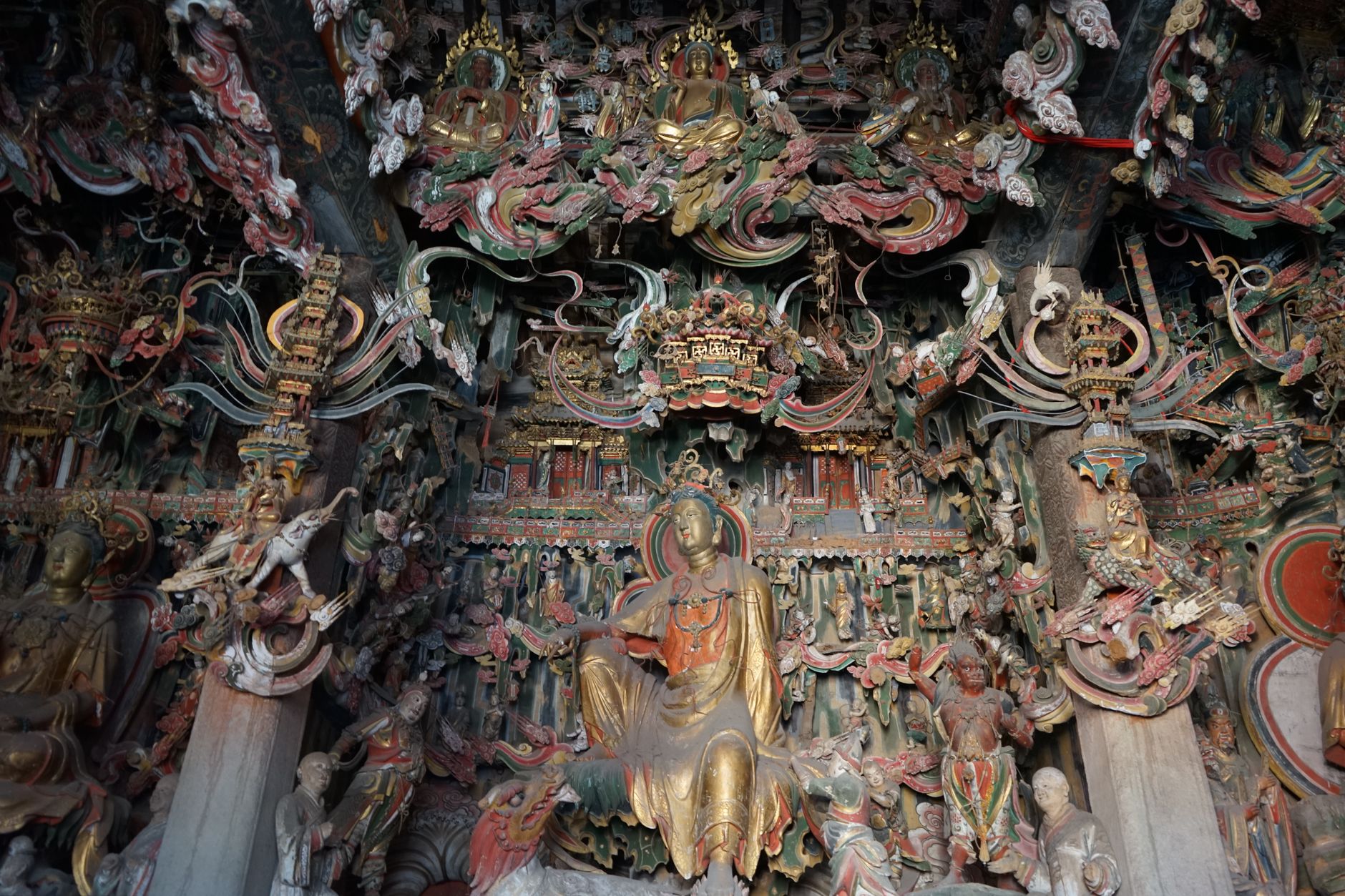 Gilded Buddhist statues and intricate carvings inside a mountain temple hall