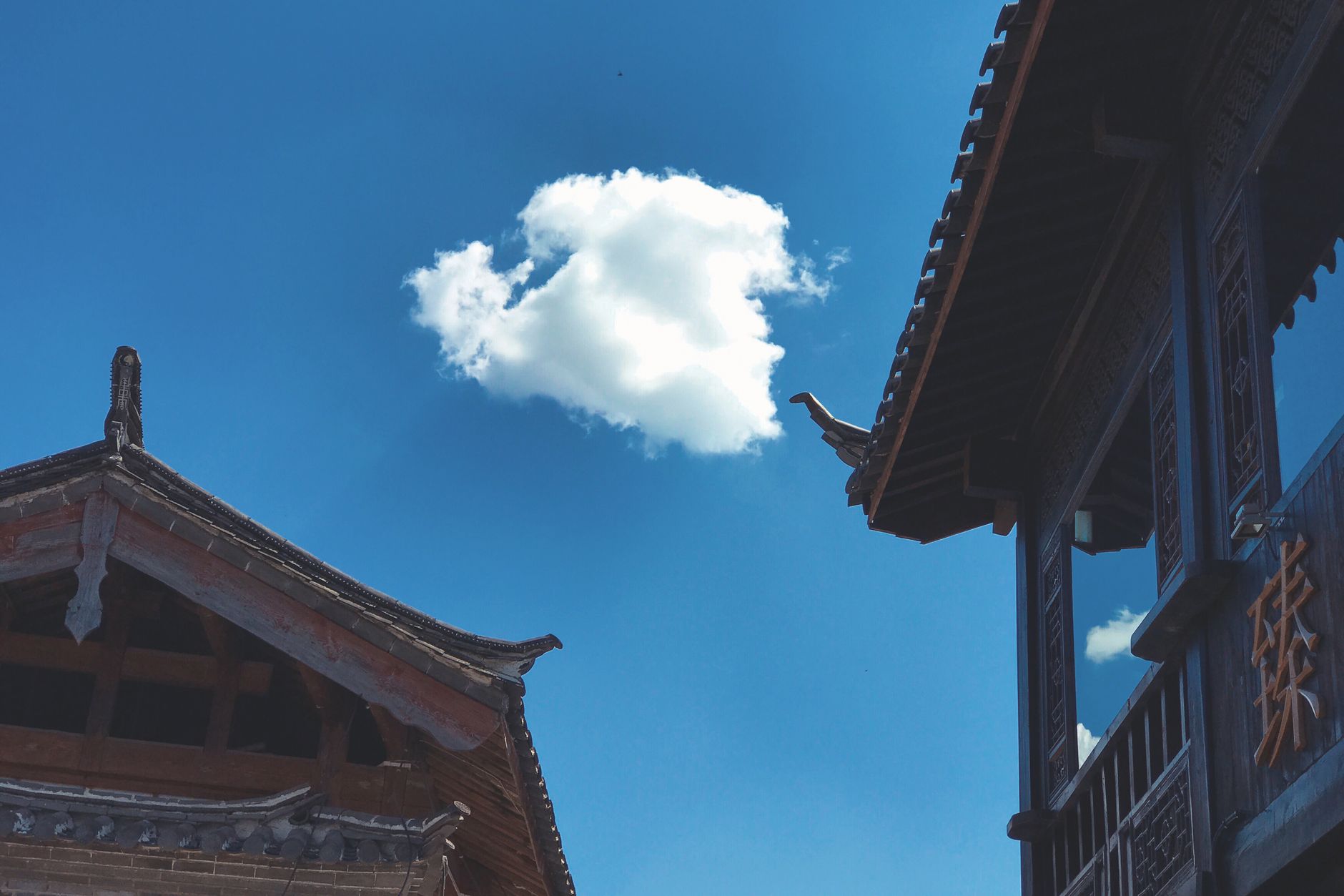 Naxi timber rooftops under a deep blue sky in Lijiang Old Town