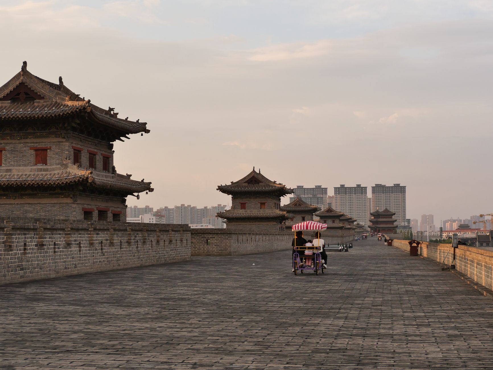 Cyclists riding along the top of the Xi'an City Wall at sunset