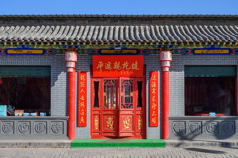 A restored grey-brick Qing-dynasty shopfront with red doors and couplets on Ming-Qing Street