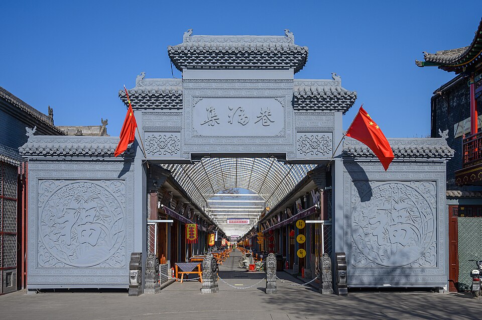 A decorative grey-brick gateway leading into a covered side lane off the main street