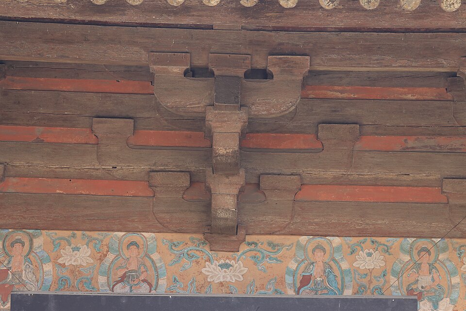 Painted Buddhist frieze beneath the carved timber brackets of the Wanfo Hall