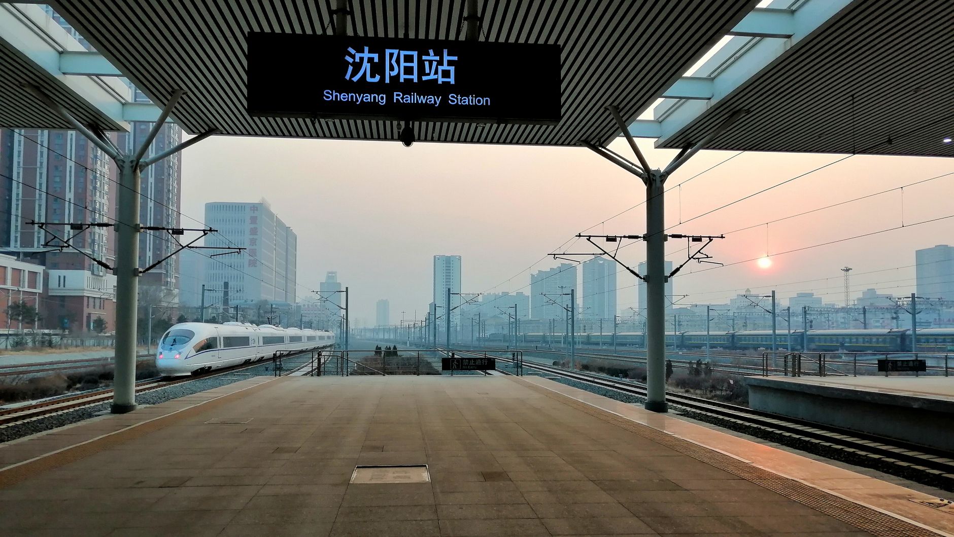 High-speed train pulling into Shenyang Railway Station at sunset