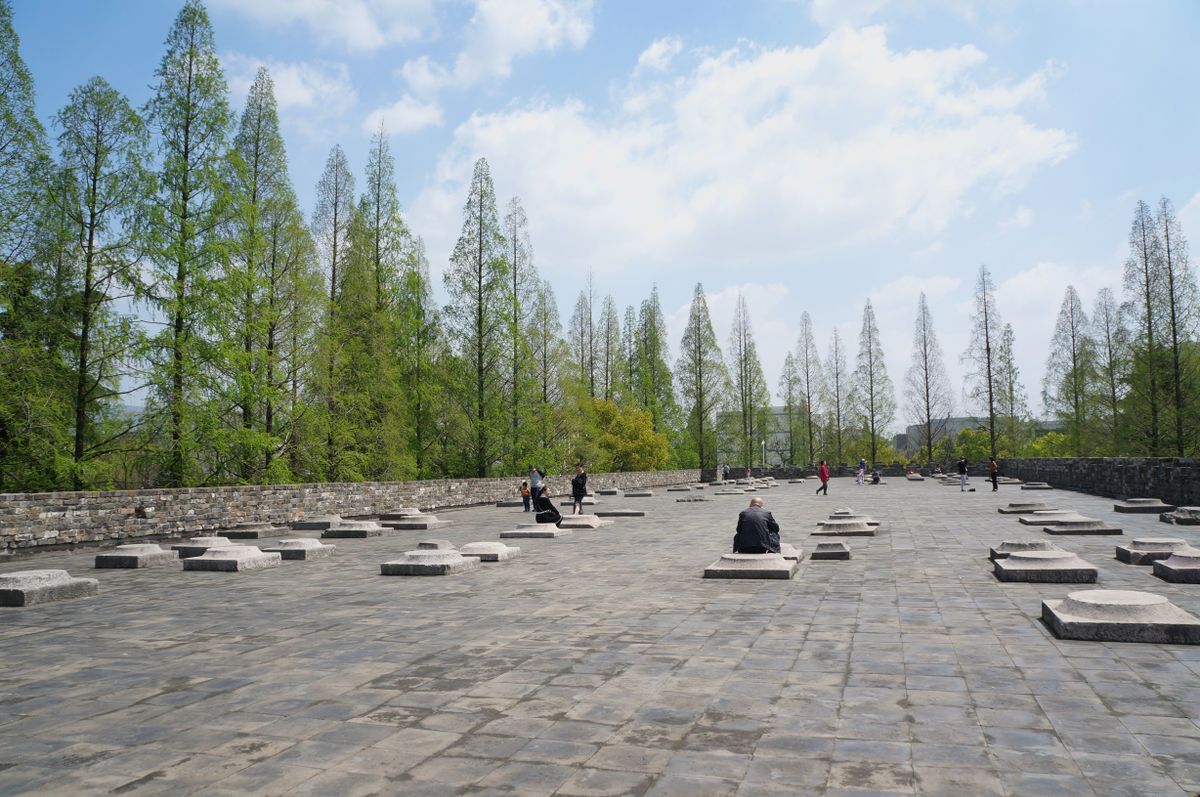 Ancient grey city wall and stone plaza under a blue sky