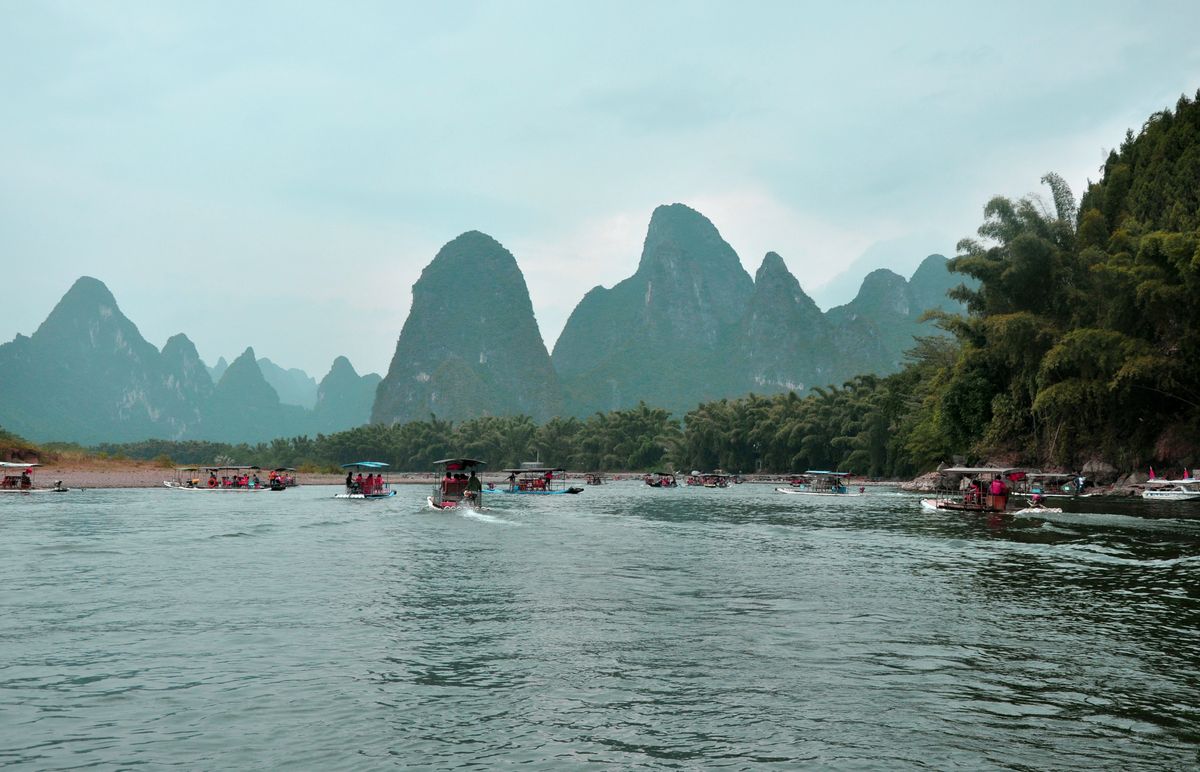 Old riverside street of Xingping with flags and karst peaks behind